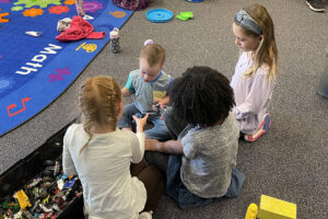 FRCS kindergarten girls play with a little boy whose family was touring the facility