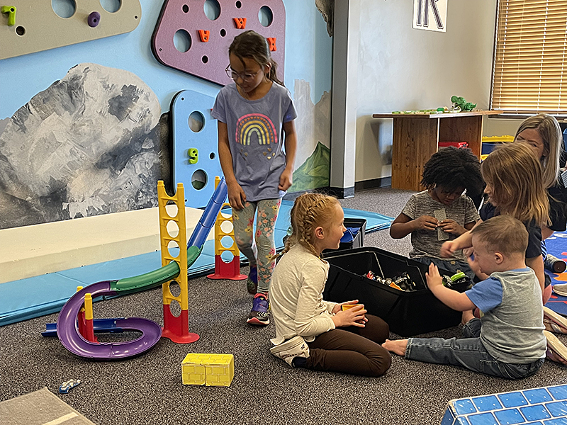 FRCS kindergarten girls play with a little boy whose family was touring the facility